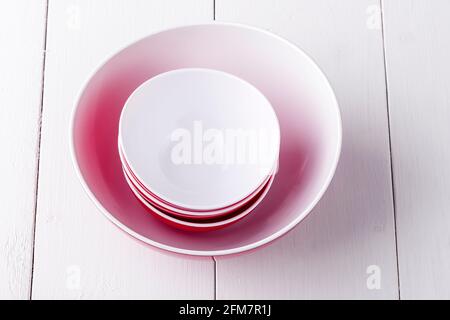 Una ciotola di insalata rossa vuota e tre tazze su a. tavolo di legno bianco Foto Stock