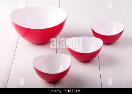 Una ciotola di insalata rossa vuota e tre tazze su a. tavolo di legno bianco Foto Stock