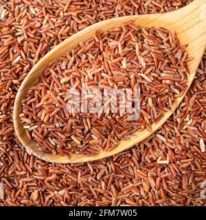 vista dall'alto del riso rosso crudo in un cucchiaio di legno da closeup Foto Stock