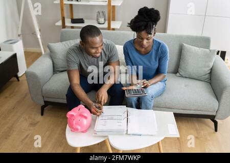 Felice coppia africana che fa il ritiro delle finanze piano e denaro bilancio Foto Stock