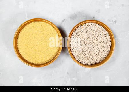 Vista dall'alto del couscous marocchino e israeliano in ceramica rotonda ciotole su tavola di cemento grigia Foto Stock