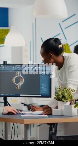 Team professionale di ingegneri del settore pesante che lavorano su computer con due monitor utilizzando software CAD con ambiente di sviluppo integrato per progettare componenti di macchinari industriali. Foto Stock