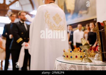 Cerimonia nuziale in una chiesa ortodossa. Lo sposo, l'uomo migliore e il sacerdote in una casseruola si trovano nella chiesa all'altare Foto Stock