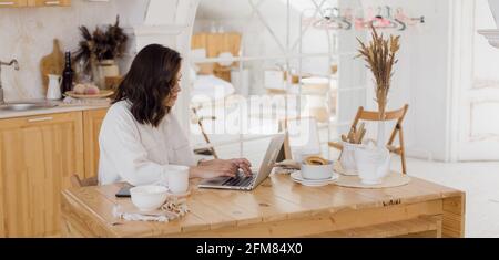Ritratto di giovane donna caucasica di successo freelancer sedersi alla scrivania a casa. Donna sicura lavora online su un notebook a casa. Foto Stock