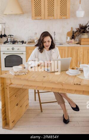 Ritratto di giovane donna caucasica di successo freelancer sedersi alla scrivania a casa. Donna sicura lavora online su un notebook a casa. Foto Stock