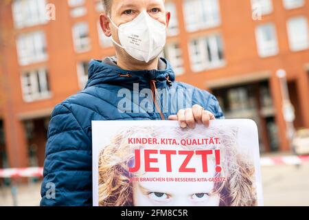 Hannover, Germania. 07 maggio 2021. Durante una manifestazione davanti al parlamento di Stato, un insegnante di asilo tiene un poster con lo slogan 'Kinder. Cura del giorno. Qualità. Ora! Abbiamo bisogno di una migliore legge Kita». Oggi, il comitato culturale del parlamento statale della bassa Sassonia sta discutendo una nuova legge sull'asilo. Credit: Moritz Frankenberg/dpa/Alamy Live News Foto Stock