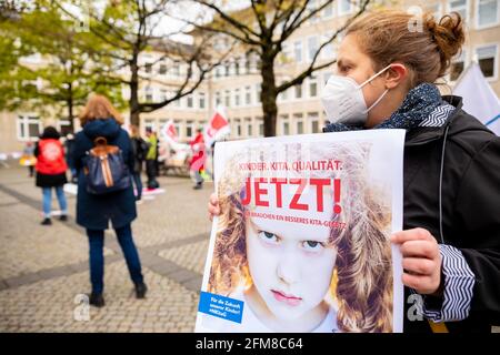 Hannover, Germania. 07 maggio 2021. Durante una manifestazione davanti al parlamento di Stato, un insegnante di asilo tiene un poster con lo slogan 'Kinder. Cura del giorno. Qualità. Ora! Abbiamo bisogno di una migliore legge Kita». Oggi, il comitato culturale del parlamento statale della bassa Sassonia sta discutendo una nuova legge sull'asilo. Credit: Moritz Frankenberg/dpa/Alamy Live News Foto Stock