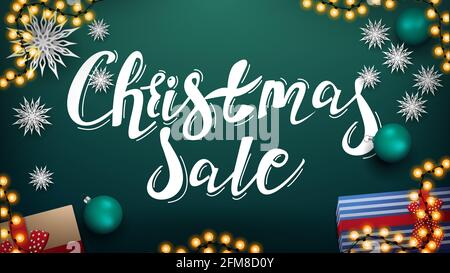 Vendita di Natale, banner sconto verde con belle scritte, garland, palline verdi, regali e fiocchi di neve di carta, vista dall'alto Foto Stock