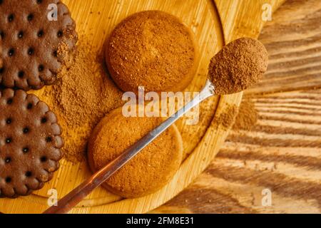 Biscotti di farinata d'avena e farciture su un vassoio. Cucchiaio con spezie o gocce di cioccolato. Cottura su sfondo di legno. Il concetto di Natale, Ringraziamento e Halloween. Foto Stock