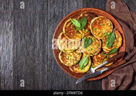 frittelle di spinaci di ceci su un piatto di argilla su un tavolo di legno scuro con hummus in una piccola ciotola, piatto, spazio libero Foto Stock