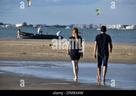 Giovane coppia che cammina sulla spiaggia sulla riva di sabbia a Port Camargue, vicino a la Grande Motte e Montpellier, Occitanie, a sud della Francia Foto Stock