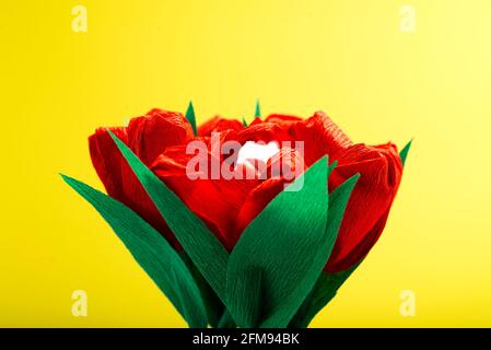 Tulipani rossi in carta e con marshmallow all'interno di un bocciolo su sfondo giallo con un posto per il testo. Foto Stock