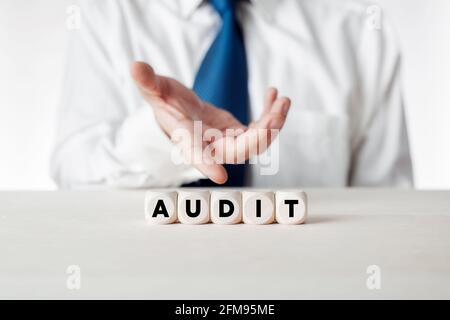 Mano di un uomo d'affari che presenta i cubi di legno con la parola audit. Concetto di finanza aziendale. Foto Stock