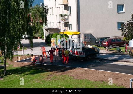 POLZELA, SLOVENIA - 13 LUGLIO 2020: I lavoratori sulla strada del paese sta posando una nuova pavimentazione in asfalto, un team di costruttori di strade allineare l'asfalto Foto Stock