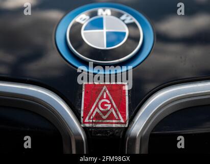 Lipsia, Germania. 07 maggio 2021. Il logo IG Metall è incastrato sotto il logo BMW su una vettura di fronte allo stabilimento BMW di Lipsia. Nella controversia contrattuale collettiva nel settore dei metalli, IG Metall ha invitato i dipendenti dello stabilimento BMW a fare uno sciopero di allarme di 24 ore. L'Unione chiede, tra l'altro, aumenti salariali del quattro per cento e un miglioramento delle norme sull'assunzione di tirocinanti. Credit: Hendrik Schmidt/dpa-Zentralbild/dpa/Alamy Live News Foto Stock