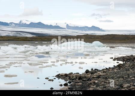 Il ghiaccio del ghiacciaio Breioamerkurjokull (posteriore) galleggia nel lago ghiacciato di Fjallsarlon nel Parco Nazionale di Vatnajokull, Islanda. Foto Stock