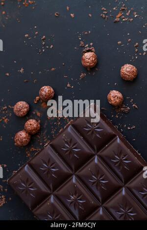 Deliziosa barra di cioccolato fondente con trucioli, briciole, palle di riso vista dall'alto sul tavolo dell'ardesia Foto Stock