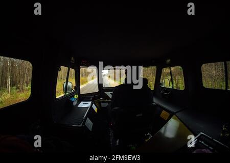 Vista dall'interno del SUV in fuoristrada. Viaggia attraverso i luoghi selvaggi in auto con traffico elevato. Vista dal sedile del passeggero al conducente Foto Stock