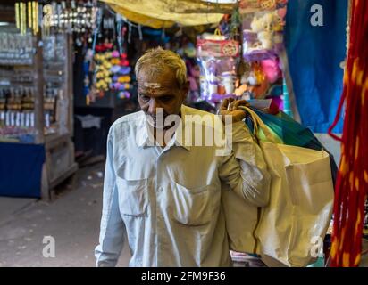 Mysore, Karnataka, India - Gennaio 2019: Un ritratto candido di un uomo indiano che cammina attraverso un mercato di strada dingy nella città. Foto Stock