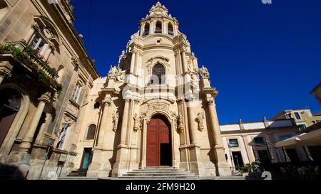 Italia, Sicilia, Sicilia sudorientale, angolo barocco, Ragusa, Centro storico, luce del mattino, chiesa di San Giuseppe, fronte e portale, vista super grandangolare dal basso diagonalmente, cielo blu, edificio sulla sinistra è il commissariato del Commissario Montalbano Foto Stock