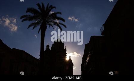 Italia, Sicilia, Sicilia sudorientale, angolo barocco, Ragusa, Piazza Duomo e Domo di San Giorgio nella retroilluminazione serale, la cattedrale e la palma su Piazza Duomo come una silhouette, il sole splende da dietro la cattedrale Foto Stock