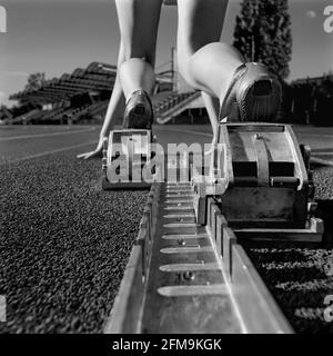 Gambe di una pista e atleta sul campo in partenza blocco Foto Stock