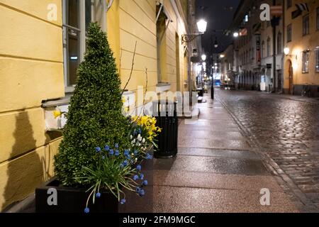 Helsinki / Finlandia - 25 APRILE 2021: Vista di un vicolo vuoto sulla zona pedonale con i riflessi del pavimento in pietra bagnata. Foto Stock