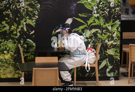 COSTA D'AVORIO, Abidjan, aeroporto, corona follia, donna cinese viaggiatore con protezione completa del corpo indossare durante Corona Pandemic tempo, bere succo in aeroporto ristorante / ELFENBEINKÜSTE, Abidjan, Flughafen, Chinesische Reisende in Schutzkleidung während der Corona Pandemie Foto Stock