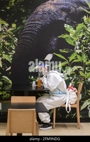 COSTA D'AVORIO, Abidjan, aeroporto, corona follia, donna cinese viaggiatore con protezione completa del corpo indossare durante Corona Pandemic tempo, bere succo in aeroporto ristorante / ELFENBEINKÜSTE, Abidjan, Flughafen, Chinesische Reisende in Schutzkleidung während der Corona Pandemie Foto Stock