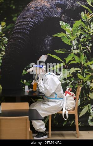 COSTA D'AVORIO, Abidjan, aeroporto, corona follia, donna cinese viaggiatore con protezione completa del corpo indossare durante Corona Pandemic tempo, bere succo in aeroporto ristorante / ELFENBEINKÜSTE, Abidjan, Flughafen, Chinesische Reisende in Schutzkleidung während der Corona Pandemie Foto Stock