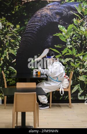 COSTA D'AVORIO, Abidjan, aeroporto, corona follia, donna cinese viaggiatore con protezione completa del corpo indossare durante Corona Pandemic tempo, bere succo in aeroporto ristorante / ELFENBEINKÜSTE, Abidjan, Flughafen, Chinesische Reisende in Schutzkleidung während der Corona Pandemie Foto Stock