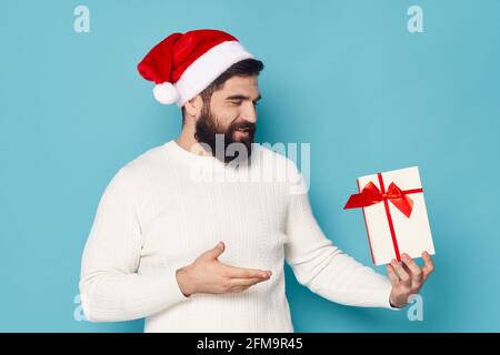 uomo bearded in pullover bianco che tiene una scatola regalo natale nuovo anno di chiusura Foto Stock