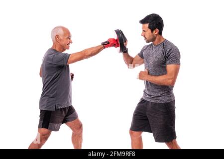 Atleta maschile anziano in ottima forma fisica, in guanti da boxe, con un allenatore, pratica di boxe. Su uno sfondo bianco isolato. Foto Stock