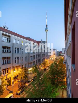 Berliner Strasse illuminato in serata con la torre della televisione di Berlino. Foto Stock