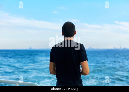 Il ragazzo getta il pane ai gabbiani che sorvolano il traghetto. Foto Stock