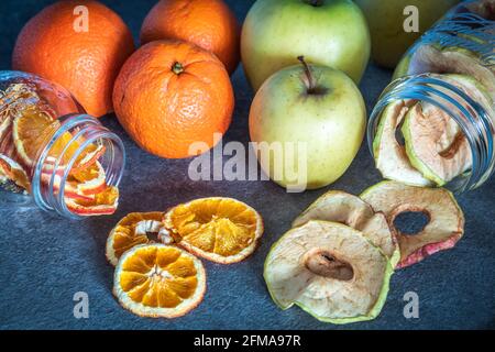 mele e arance fresche di frutta e fette di mela e di arancia disidratate e conservate in contenitori di vetro, preparazioni fatte in casa; Foto Stock