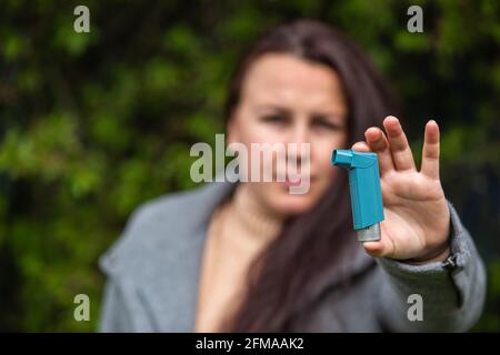 Giovane donna che tiene un inalatore di astma contro gli attacchi nelle sue mani, concetto di sanità Foto Stock