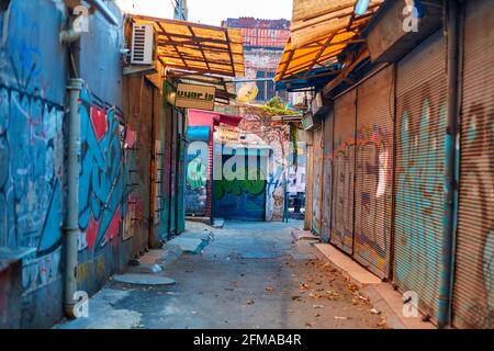 Strada del mercato stretta coperta di graffiti. Le tapparelle dei negozi sono chiuse. Ghetto. Foto Stock