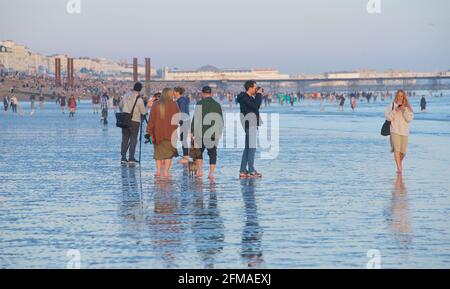 Persone che camminano sulla spiaggia a bassa marea, Brighton Palace Pier sullo sfondo. Brighton & Hove, Sussex, Inghilterra, Regno Unito Foto Stock