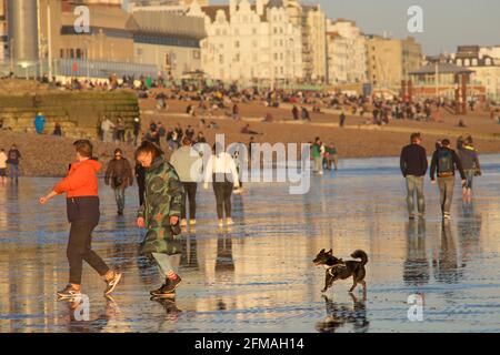 I beachgoers sulla spiaggia di Brighton durante una bassa marea, nel tardo pomeriggio, in primavera. Brighton, Sussex, Inghilterra Foto Stock