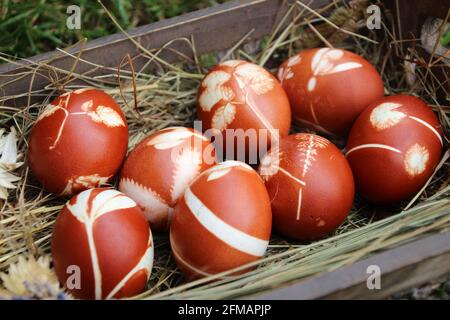 Uova di Pasqua tinte con colori naturali in un cestino con fieno Foto Stock