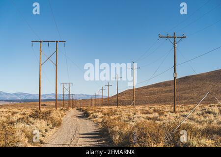 Strada sterrata lungo i poli di potere in California deserto alto contro cielo blu Foto Stock