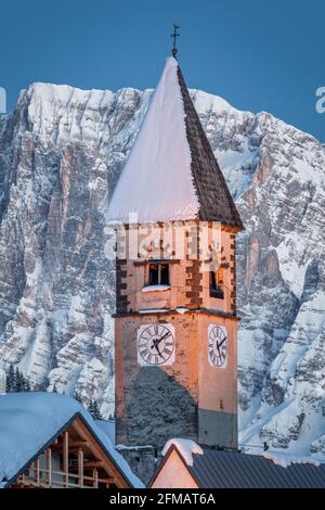 La torre dell'orologio della chiesa di Sappade in inverno, sullo sfondo il monte Civetta, Dolomiti. Comune di Falcade, Belluno, Veneto, Italia Foto Stock