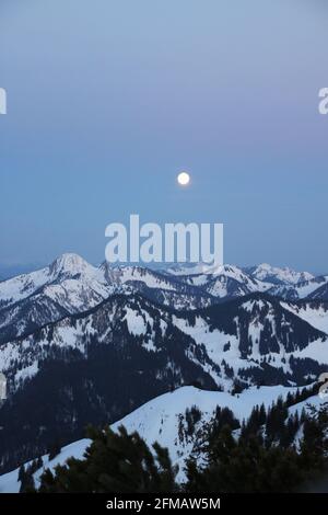 Dal Auerspitze a nord, la luna di cornice sulle montagne da sinistra a destra Risserkogel (1825 m), Blankenstein (1768 m), Bendiktenwand (1799 m), Sezberg, Hirschberg, Wallberg, poco prima dell'alba. Europa, Germania, Baviera, alta Baviera, Alpi Bavaresi, Mangfall Mountains, Spitzingsee Foto Stock