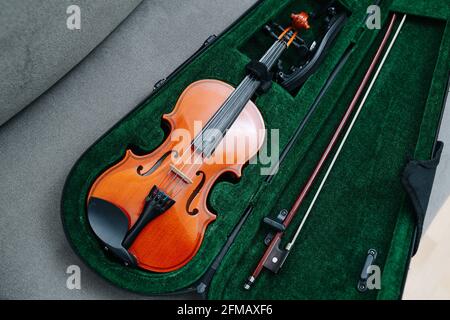 Violino, prua e sistema di supporto sistemati delicatamente in una custodia drappeggiato in un panno giallo. Angolo alto. Foto Stock