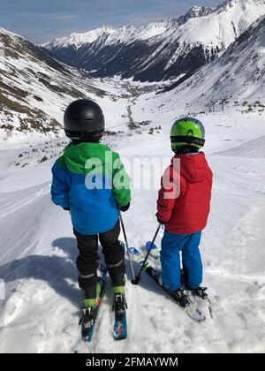 Due bambini sciatori guardano a Galtür, Galtür ski area, Silvapark, Silvretta, pista da sci, Montagne, paesaggio invernale, Verwallgruppe, Galtür, Paznauntal, Tirolo, Austria Foto Stock