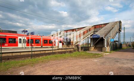 Germania, Sassonia-Anhalt, Schönebeck, un treno passeggeri attraversa una traversata pedonale arrugginita e coperta. Foto Stock