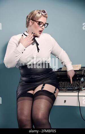 Biondo pin-up nel look segretaria con macchina da scrivere Foto Stock