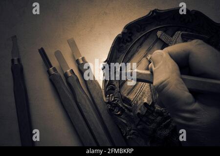 Uomo che intaglia legno con scalpelli, facendo lapide. Con tonalità di colore ed effetto di illuminazione Foto Stock