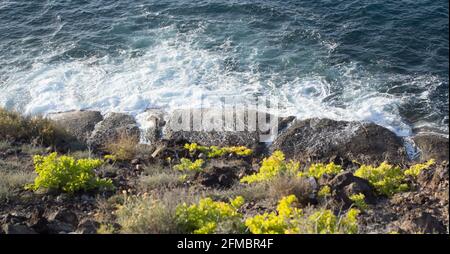 Onde oceaniche che fanno piccoli spruzzi sulla riva di Tenerife Foto Stock